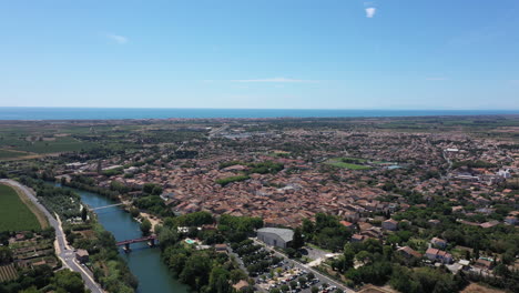 Luftaufnahme-Der-Stadt-Serignan,-Sonniger-Tag,-Okzitanien,-Mittelmeer-Im-Hintergrund